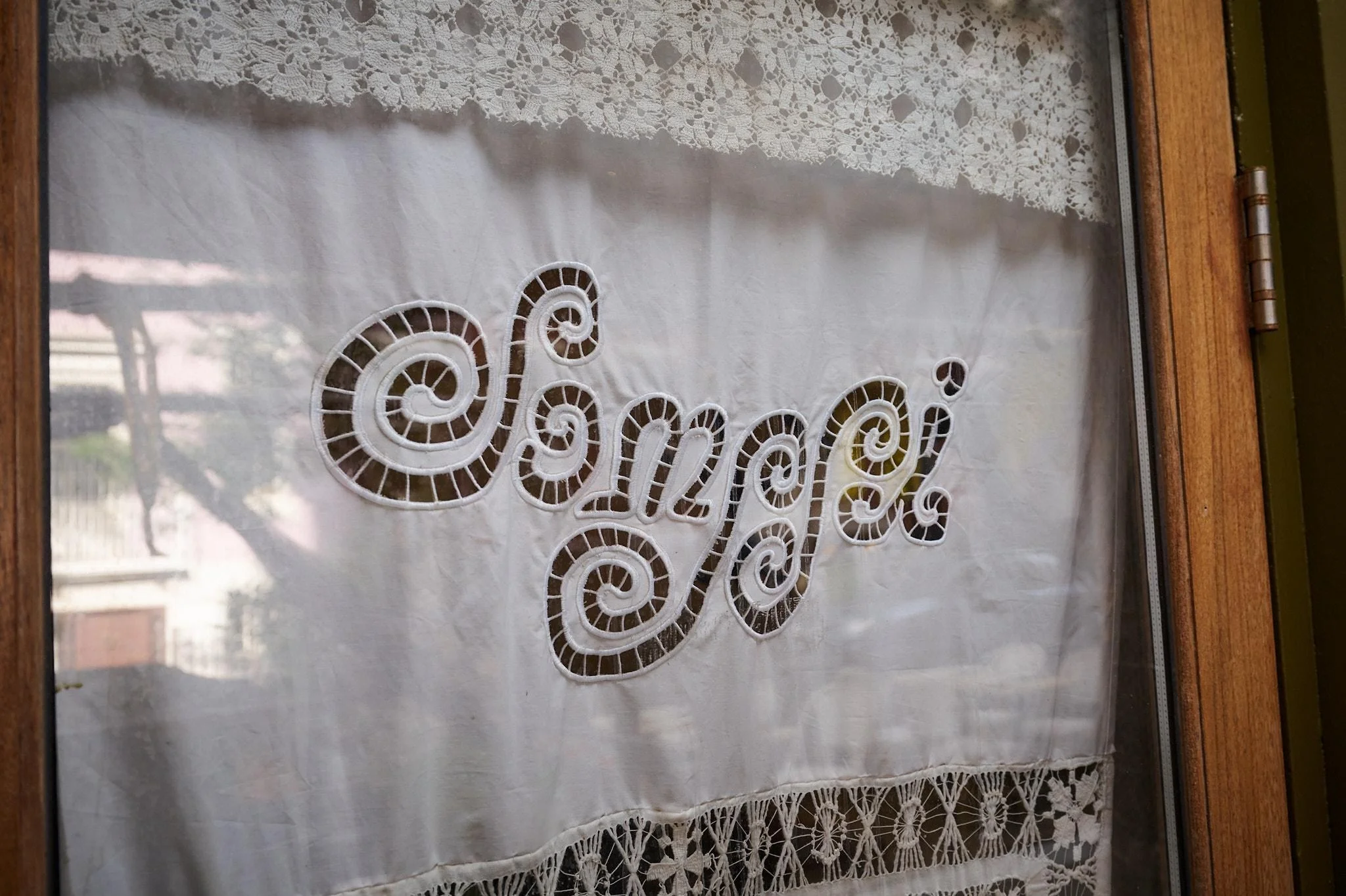 a custom curtain bearing the name of the new york city restaurant somssi hangs in a window